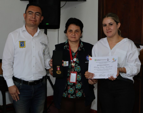 Franklin Henao y Camila Arroyave, de la Escuela Taller de Salamina, condecoraron a Marleny Gómez por su trabajo con las víctimas del conflicto armado en este municipio.