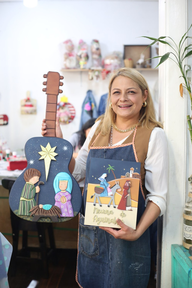 Claudia Yaneth Ramírez junto con la guitarra y novena navideña que son los diseños para este año en su taller.