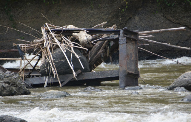Piedras y troncos arrastrados por la corriente del río Cauca quedaron atrapados entre los hierros retorcidos de los vestigios del puente. 