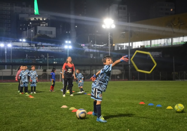 Durante las sesiones, los niños se dividen en grupos y trabajan con tres profesores, entre ellos Jessica Ospina y Santiago Monroy. Las rutinas incluyen ejercicios con balón, reacciones rápidas y coordinación motriz. En la imagen hace un lanzamiento Raphael García Loaiza.