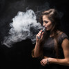 chica-sexy-vestido-negro-fumar-cigarrillo-electronico-pared-oscura
