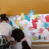 Niños pintan sus manos en un mural.