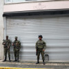 Integrantes de Fuerzas Armadas vigilan un área frente a locales comerciales cerrados este miércoles, en el centro de Cali (Colombia).
