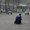 La gente se transporta con sus motos por una calle inundada en Hanoi (Vietnam).
