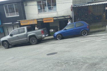 Los carros parqueados obstruyendo el paso por la cebra. 