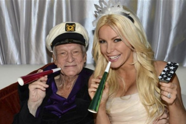 Hugh Hefner con una conejita Playboy sentados en un sofá