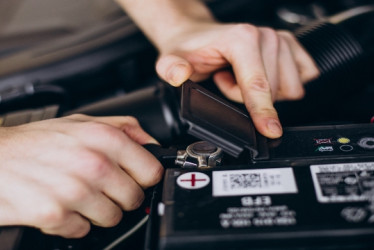 Hombre revisando la batería de un carro.