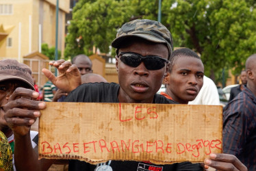 Un partidario de los soldados golpistas sostiene un cartel que dice "Bases (militares) extranjeras, salgan", durante un mitin frente al edificio de la Asamblea Nacional en Niamey (Níger). Soldados amotinados afirmaron haber derrocado al presidente Mohamed Bazoum, elegido democráticamente, en un discurso televisado el 26 de julio por la noche.