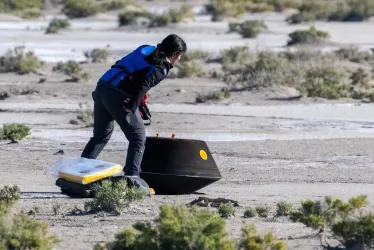 Imagen proporcionada por la NASA en la que se observa a la ingeniera de seguridad del sistema Lockheed Martin, Victoria Thiem, realizando comprobaciones preliminares en la cápsula de retorno de muestra de la misión OSIRIS-Rex poco después de aterrizar en el desierto en Utah del Departamento de Defensa.