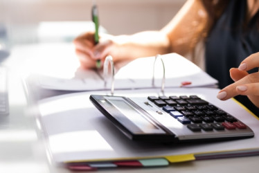 Mujer en un escritorio con un cuaderno y una calculadora.