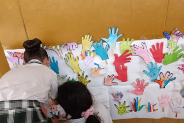 Niños pintan sus manos en un mural.