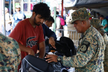 Fotografía del 8 de octubre de 2024 de un migrante siendo requisado por un integrante del Servicio Nacional de Fronteras, en el puesto de Bajo Chiquito (Panamá).