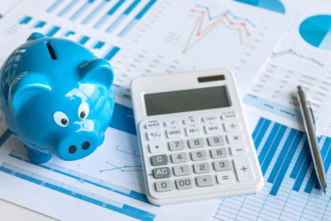 Calculadora y lapicero encima de una hoja con números.