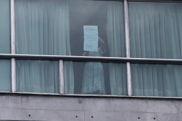 Una persona sostiene un cartel desde una ventana del hotel Decápolis este martes, en Ciudad de Panamá (Panamá). 