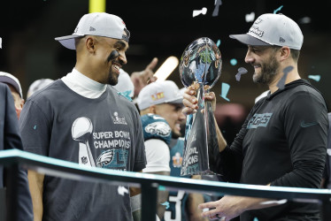 El entrenador en jefe de los Philadelphia Eagles, Nick Sirianni (der.), y el mariscal de campo Jalen Hurts admiran el trofeo Vince Lombardi del Super Bowl LIX.