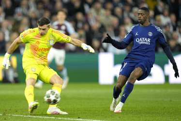 El portero Emiliano Martínez (izq.) del Villa juega el balón delante de Ousmane Dembele del PSG 