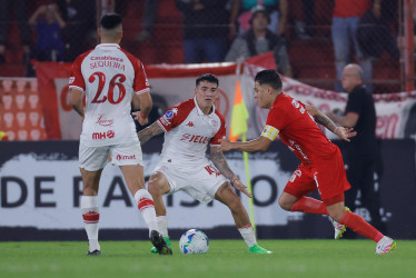 Rodrigo Cabral (c), de Huracán, disputa el balón con Juan Fernando Quintero, de América de Cali, en el partido que el Globo y la Mecha empataron a cero en Buenos Aires.