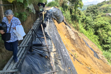 Dos mujeres cruzan por el puente artesanal que está sobre la vía colapsada de la vereda Java, de Manizales. 