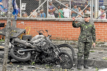 Una integrante del Ejército camina al lado de los escombros ocasionados por el atentado ocurrido cerca a la estación de Policía del barrio Meléndez, al sur de Cali.