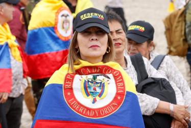 Una mujer sostiene una banderA en apoyo al senador y precandidato presidencial Miguel Uribe Turbay. 