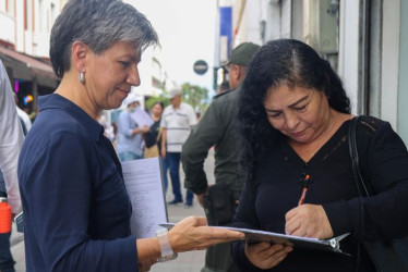 Claudia López tomando la firma de una ciudadana para cumplir con el requisito de la Registraduría y continuar su carrera por la presidencia de Colombia.