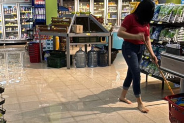 Este es un supermercado se inundó a raíz del daño de la tubería. Una empleada trapea el piso para retirar el agua. 