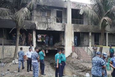 Miembros de la Fuerza Aérea de Bangladés y otras agencias de investigación investigan la escena después de que un avión de entrenamiento de la fuerza aérea se estrelló en el campus de Milestone College, en Daca.