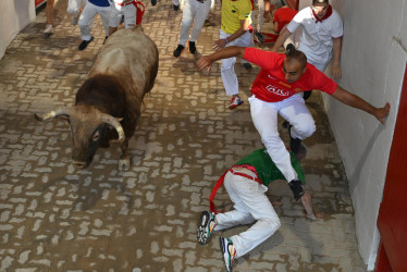 Varios mozos acompañan a uno de los toros de la ganadería Victoriano del Río Cortés en el callejón de entrada a la Plaza de Toros durante el cuarto encierro de los Sanfermines, este jueves, en Pamplona. 
