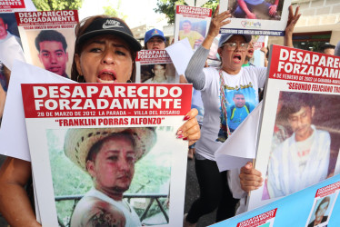 Familiares de víctimas de desaparición forzada protestan este sábado sosteniendo carteles con fotos de sus allegados desaparecidos, en Cúcuta (Colombia). 