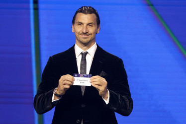 El exfutbolista sueco Zlatan Ibrahimovic sostiene el papel del Barcelona durante el sorteo de la fase de liga de la UEFA Champions League en el Foro Grimaldi de Mónaco.