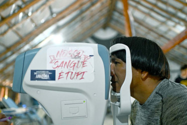 El jefe indígena Akauã Kamayurá hace una prueba visual en un equipo médico, con las letras que dicen en portugues 'Nuestra sangre es Tupi'. 