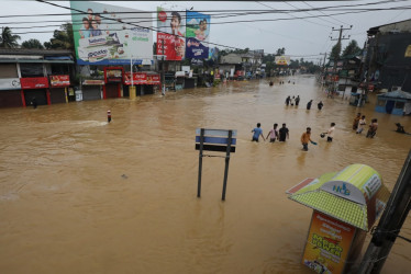 as víctimas de las inundaciones en Sri Lanka caminan por una carretera inundada durante las fuertes lluvias en un suburbio de Colombo