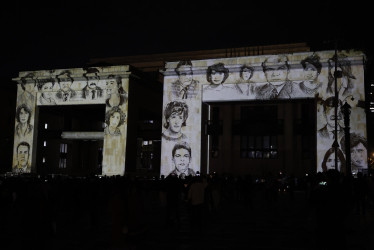 Fotografía donde se observa la proyección de rostros de víctimas sobre la fachada del Palacio de Justicia durante un homenaje este jueves, en Bogotá (Colombia).