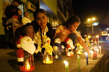 María Paz Álvarez (i) y su sobrina Antonella Arciniegas acomodan los muñecos de nieve y Papá Noel que llevan los nombres de los siete integrantes de la familia, además de la mascota. Están hechos de material recicable y las dos pequeñas disfrutan del alumbrado en el barrio Bengala de Manizales.