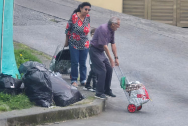 Dos adultos mayores con una niña tuvieron que bajar del anden para poder continuar con su camino debido a la basura que había en esa esquina.