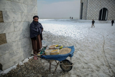 Un vendedor ambulante afgano espera a sus clientes bajo la nieve en Kabul, Afganistán. 