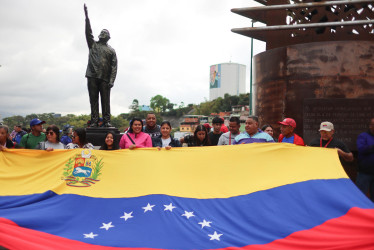Personas junto a la estatua de Hugo Chávez en Caracas conmemoran el decimotercer aniversario de la muerte del presidente.