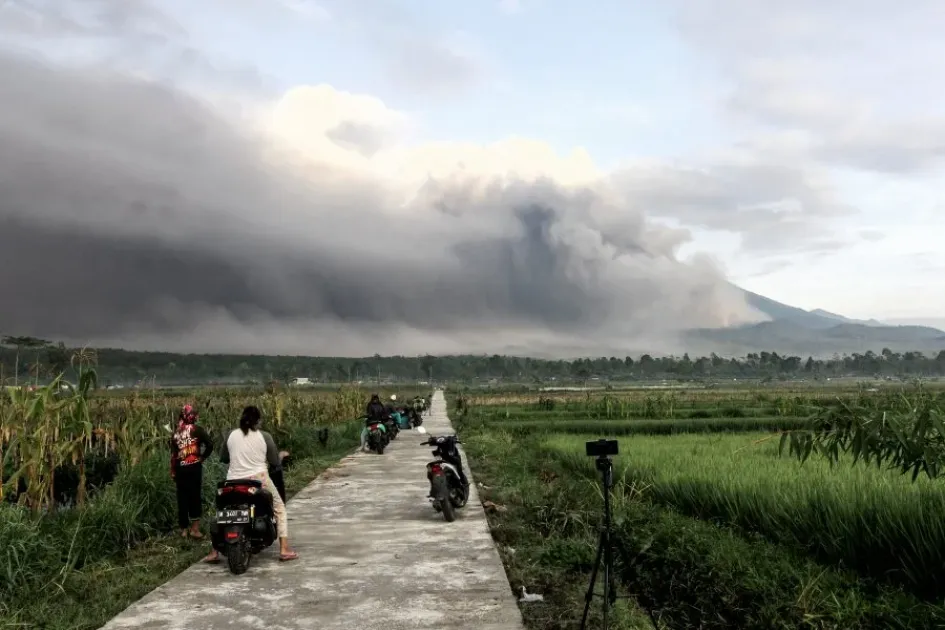 El Monte Semeru arroja materiales volcánicos al aire mientras la gente observa durante una erupción en Lumajang, Java Oriental, Indonesia.