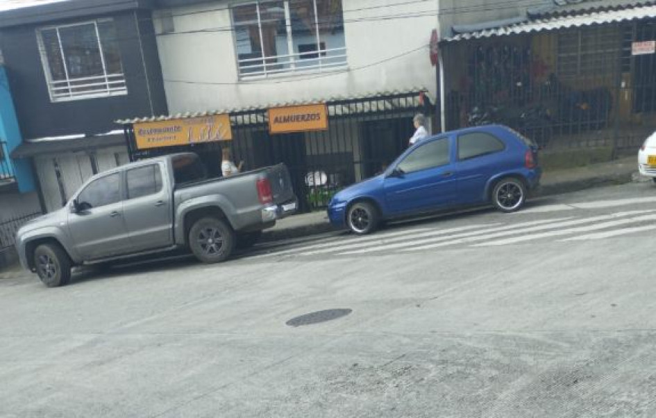 Los carros parqueados obstruyendo el paso por la cebra.