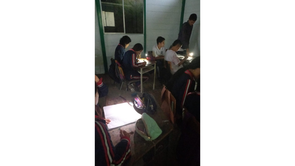 Estudiantes de bachillerato de la I.E. Pío XII, de Neira, recurren a lámparas de celulares por falta de energía y luz natural. 