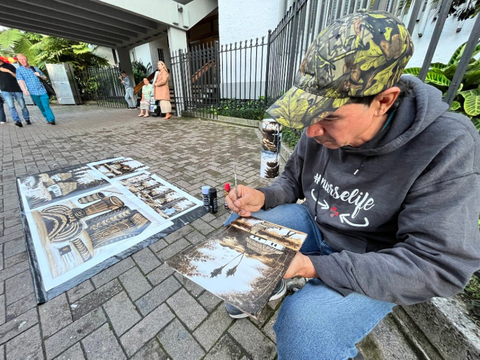 Antonio José Hernández llega todos los días al frente del Club Manizales y expone sus cuadros de paisaje que elabora con tintilla de madera, pátina y varsol sobre papel fotográfico.