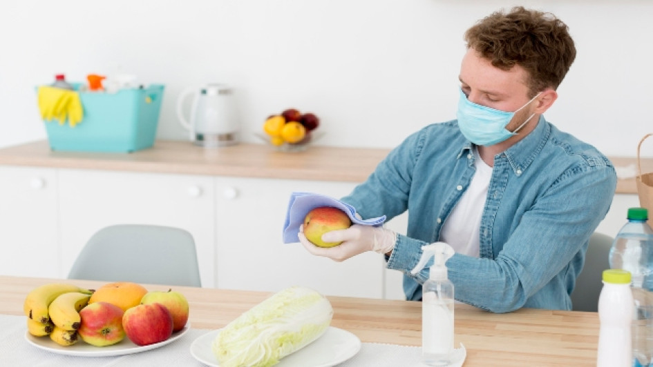 Hombre usando tapabocas desinfecta frutas con un pañuelo.