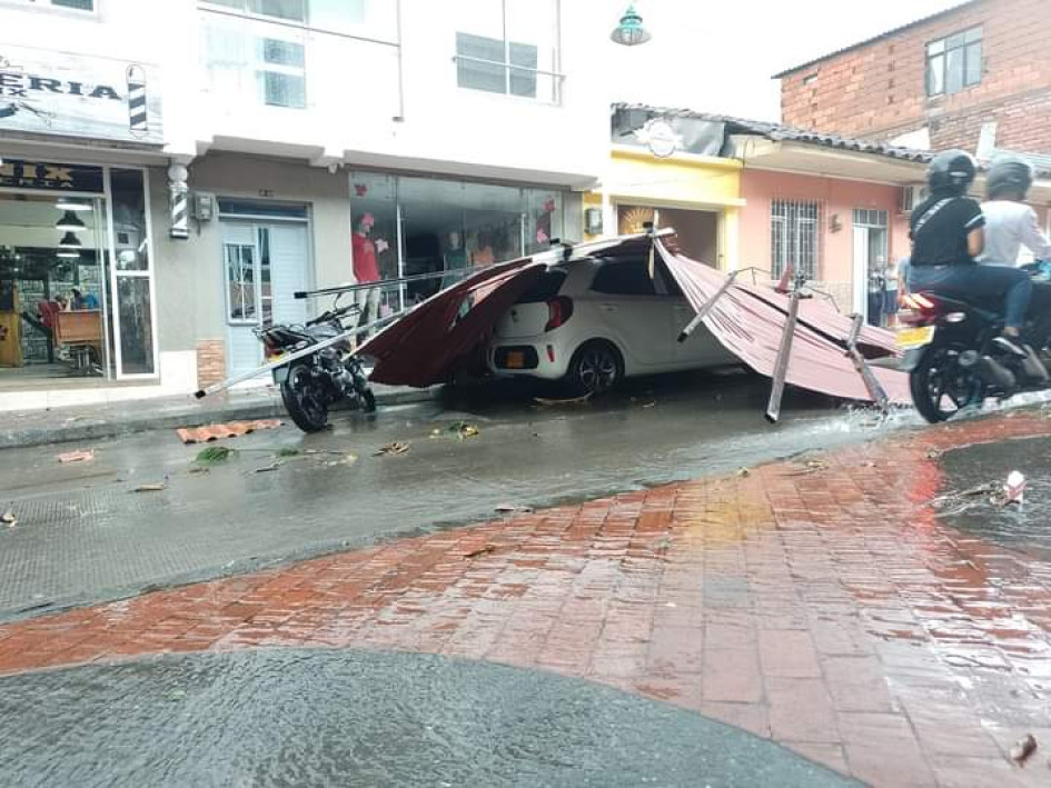 Un vehículo particular blanco quedó atrapado bajo unas láminas metálicas tras el vendaval.