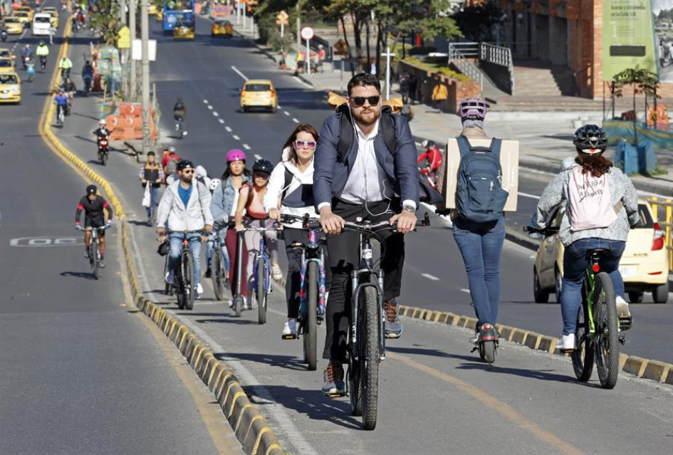 Personas transitan hoy en bicicleta y patineta eléctrica durante el día sin carro, en Bogotá.