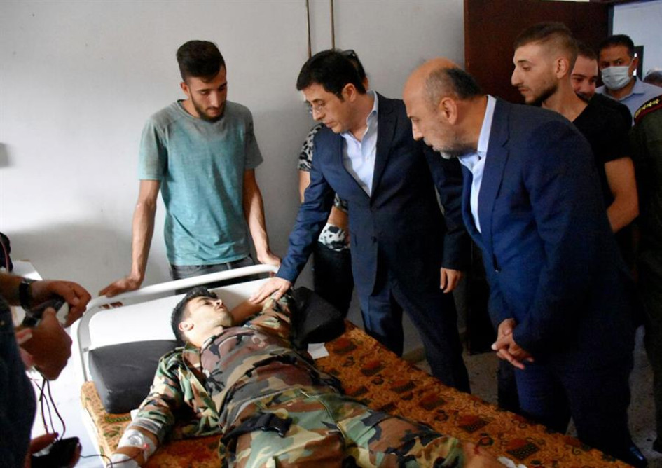 La foto proporcionada por la agencia oficial de noticias árabe siria (SANA) muestra al Ministro de Salud sirio, Hassan al-Ghabash (C), visitando a un herido después de un ataque con aviones no tripulados que tuvo como objetivo una ceremonia de graduación de la academia militar Homs, Siria.