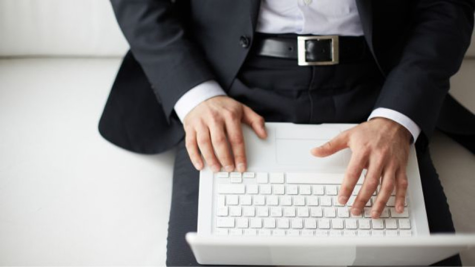 Hombre elegante con un computador portatil blanco en sus piernas.