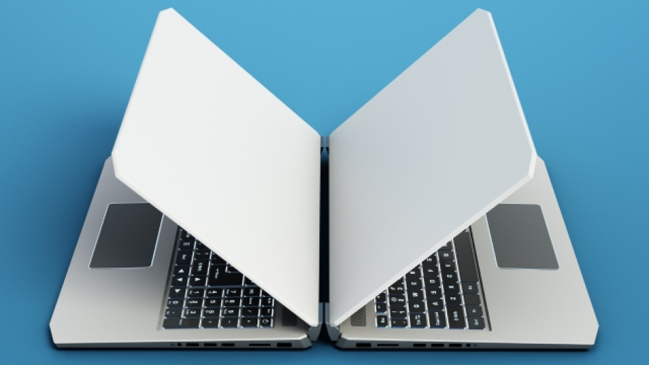 Dos computadores portátiles uno al frente del otro en una superficie azul.