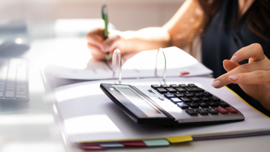Mujer en un escritorio con un cuaderno y una calculadora.