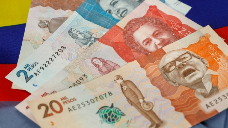 Billetes de pesos colombianos con una bandera de Colombia detrás.