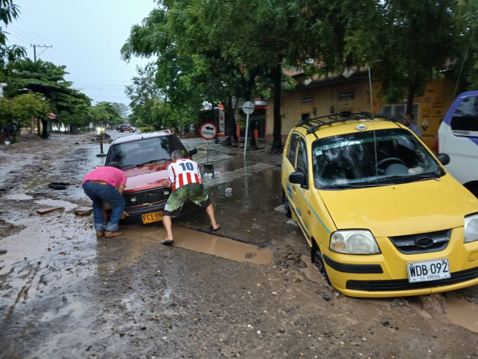 Dos conductores intentan sacar sus vehículos de un agujero que se inundó a raíz de las lluvias registradas en la madrugada de ayer en La Dorada